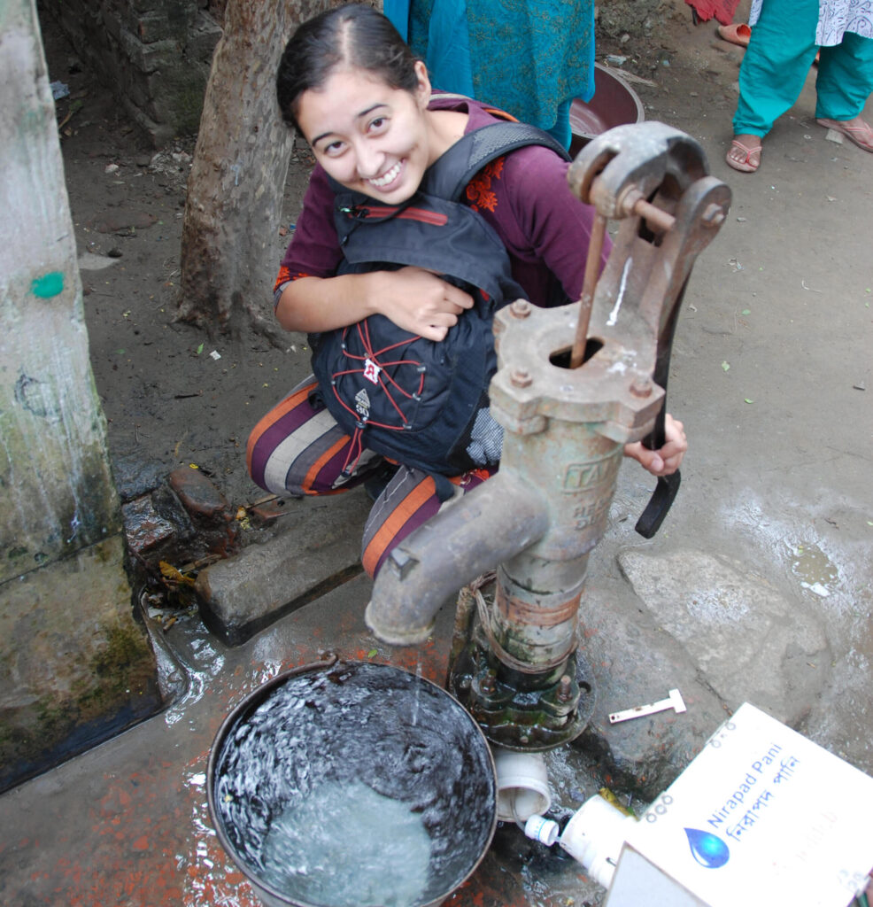 Crider, kneeling, tests an early prototype of the TuriTap at a community tap in Bangladesh.