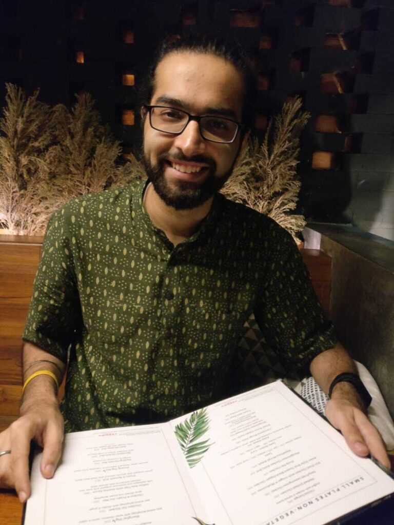 A man holding a menu, looking up to smile at the camera