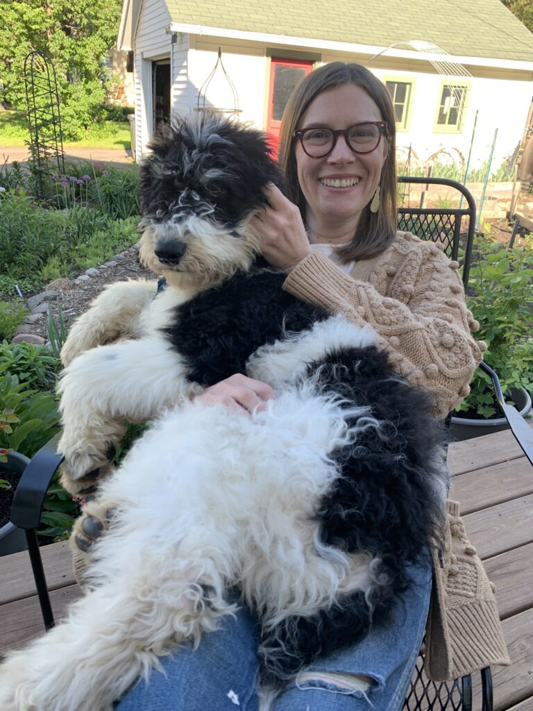 A woman, Anna, sitting in a backyard with a dog in her lap