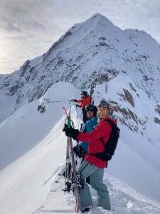 A woman and several other people holding skis on a snowy mountain