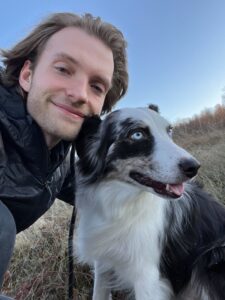 A man and a dog outside with blue sky in the background