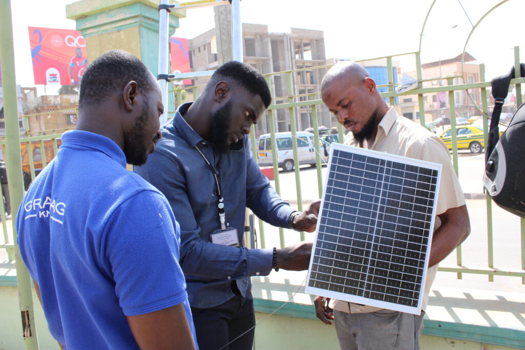 Three men set up an air quality monitor in The Gambia.