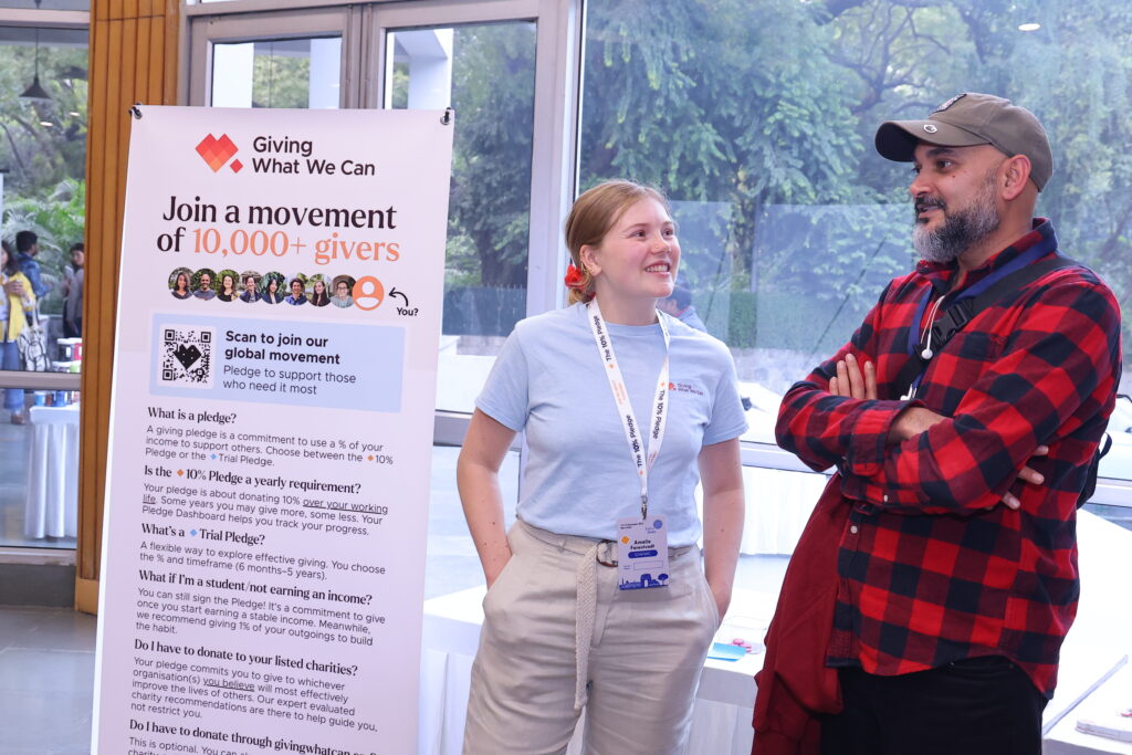 A Giving What We Can staff member speaks with an attendee at EA Global.